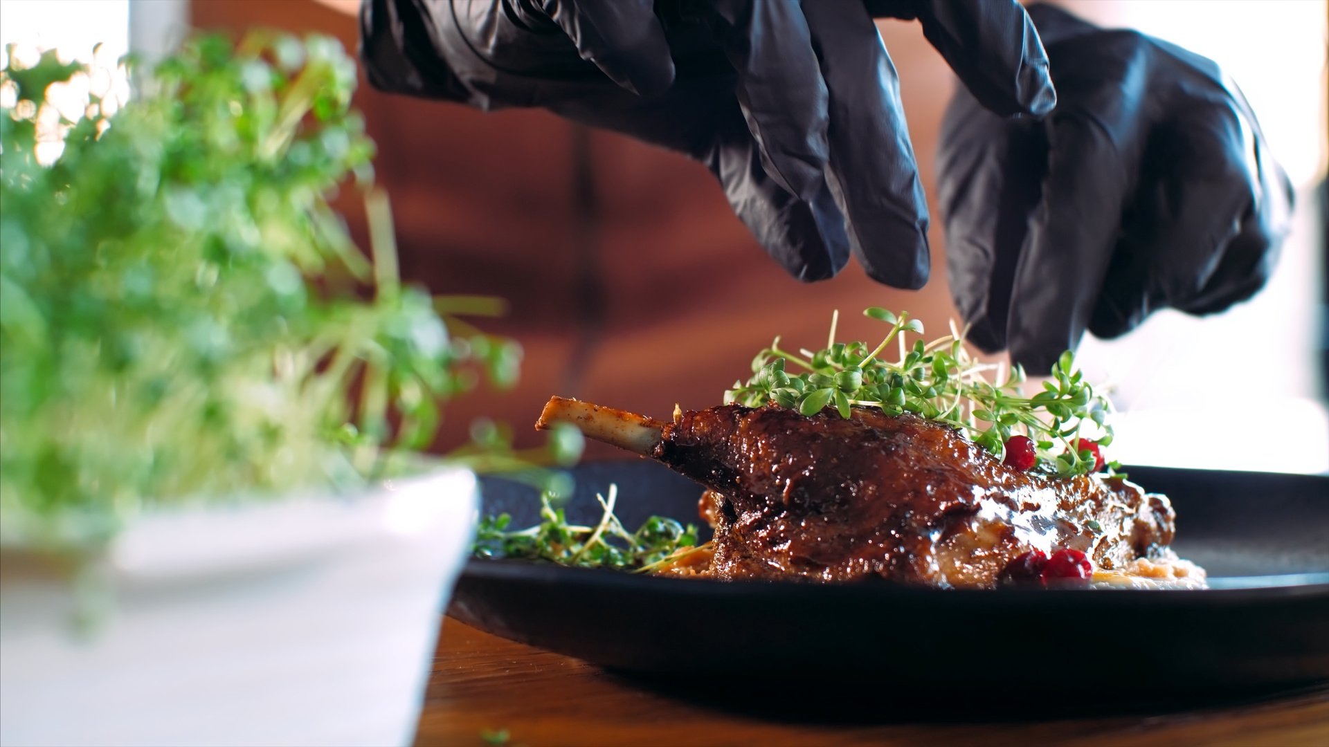 Chef adding a microgreens on roasted duck at restaurant