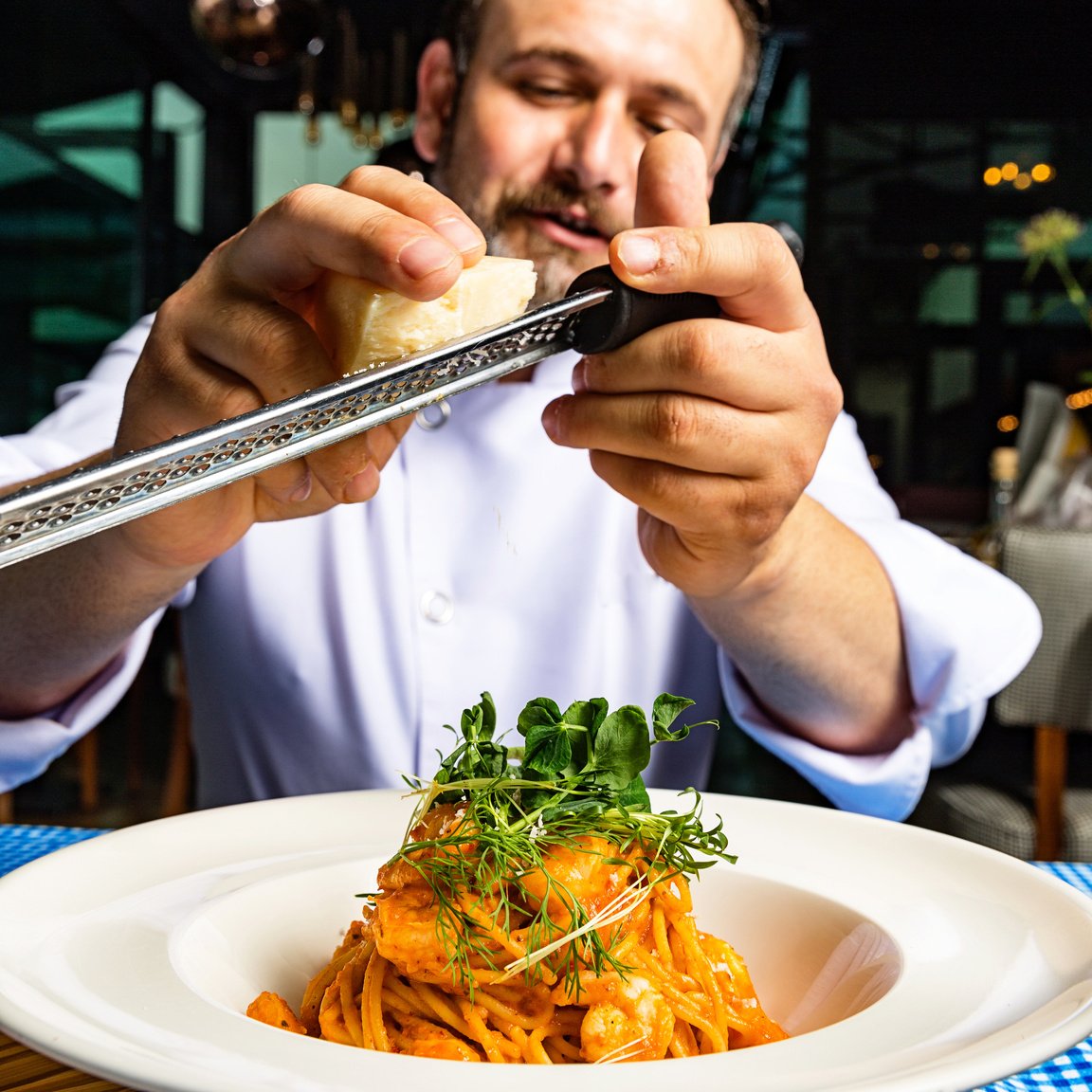 Chef Styling Plate of Spaghetti With Seafood and Microgreens